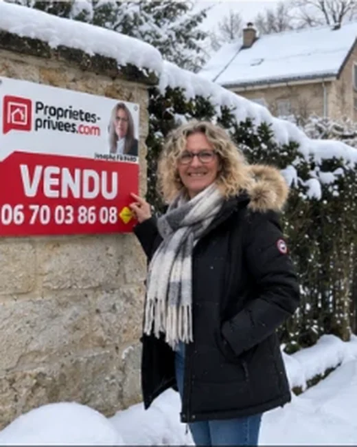 Josepha Favard devant un panneau VENDU, sous la neige